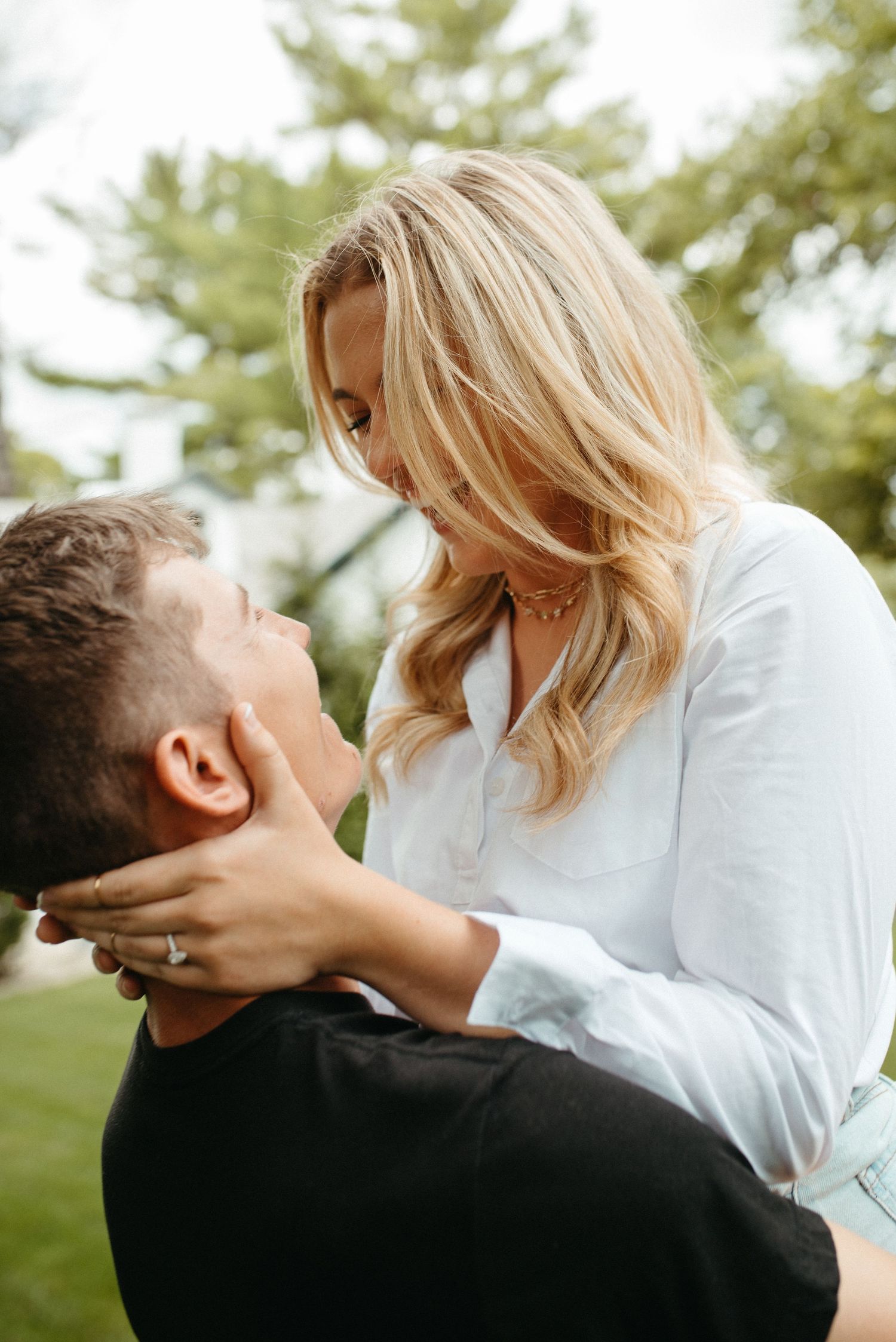Romantic couple sharing tender moment outdoors with hands cupping face.