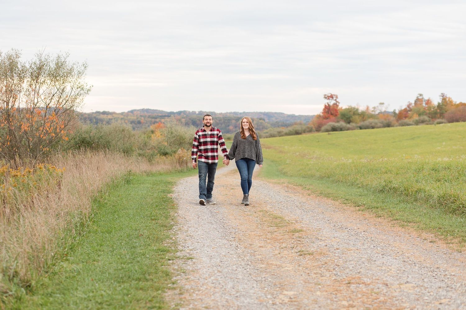 A gravel path winds through green fields and autumn trees in a pastoral landscape.