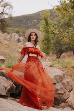 Elegant red tulle dress contrasts against rugged mountain scenery and autumn foliage.