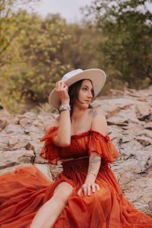 An elegant orange off-shoulder dress contrasts beautifully with natural rock formations.