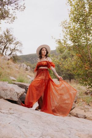 Red dress creates elegant movement against rocky mountain setting.