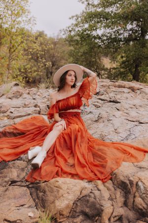 A billowing burnt orange gown creates dramatic movement against rugged rock formations.