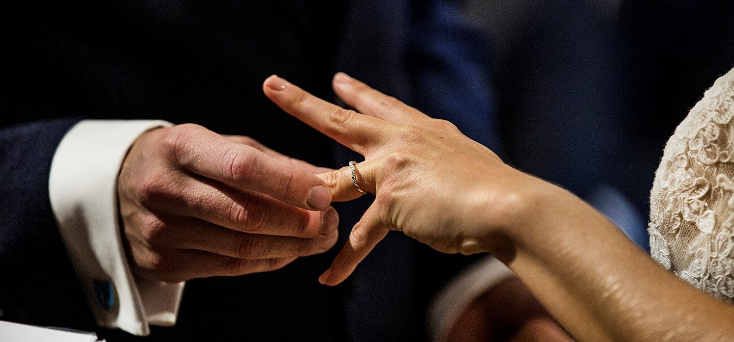 Close-up of hands exchanging rings during a wedding ceremony.