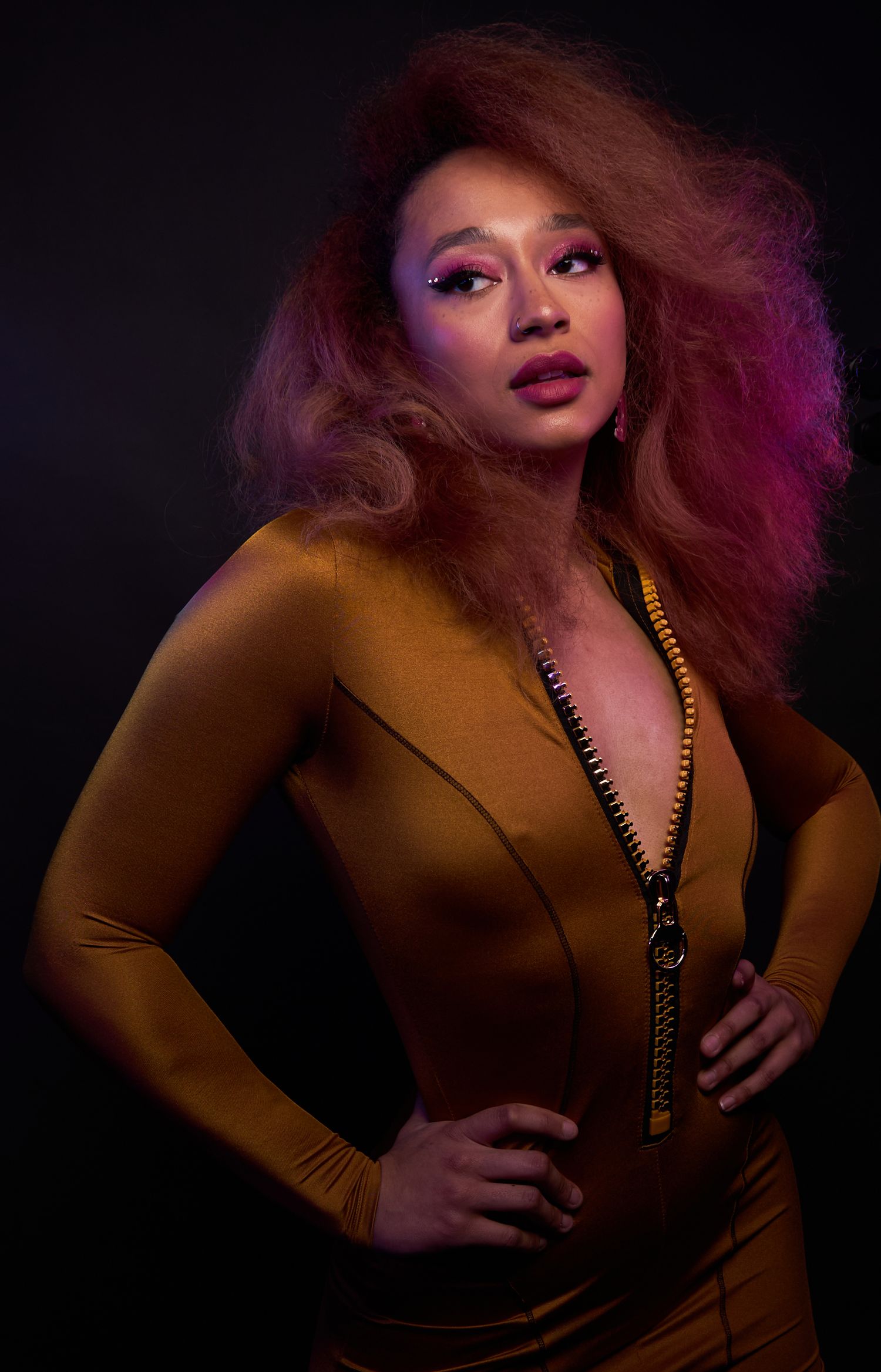 Fashion portrait in mustard dress with dramatic lighting against dark background.