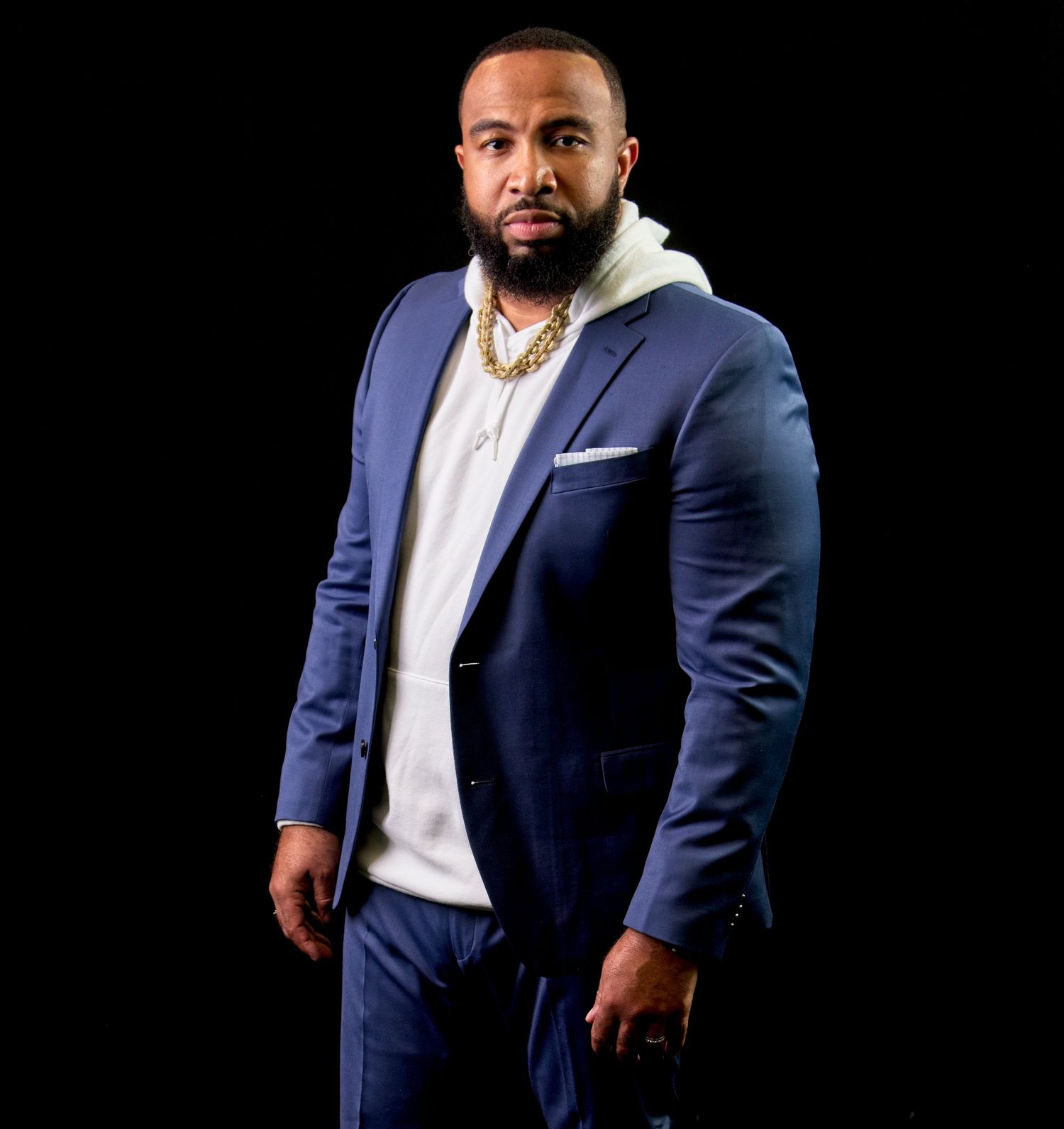 Professional studio portraits in navy suit and white shirt against black background.