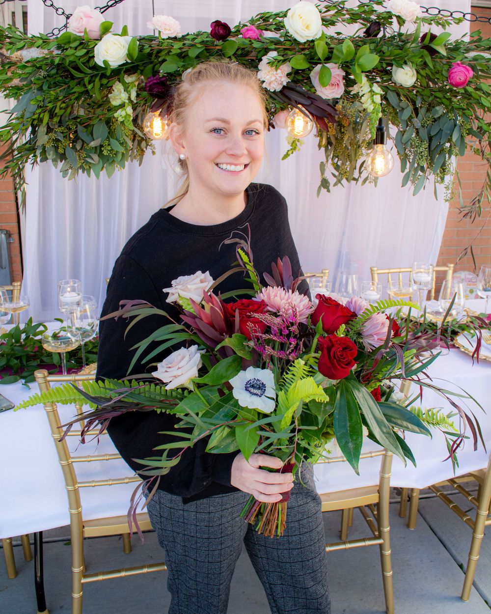Wedding florists arranging burgundy and pink floral arrangements on a decorated table.
