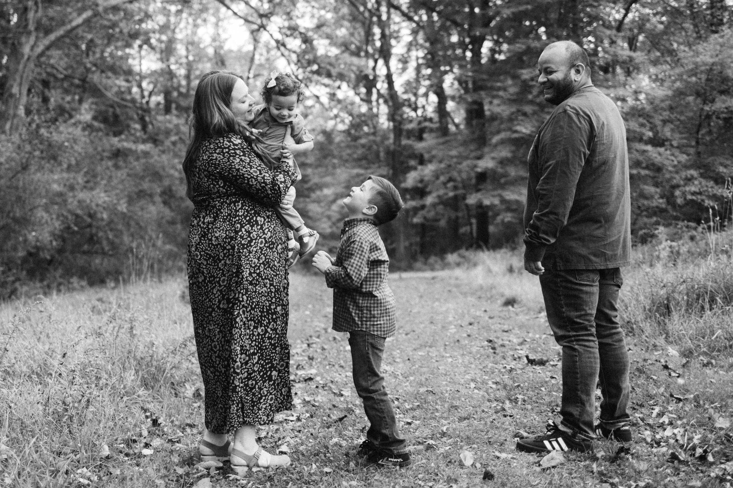 Family enjoying a casual moment together outdoors in a wooded black and white setting.