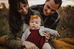 Family sharing tender moment with baby during autumn sunset photoshoot.