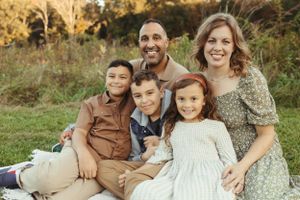 Family of five sitting together outdoors during autumn photo session.