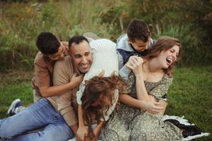 Happy family playing and laughing together with their dog on grass.