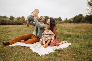 Family having fun during picnic on blanket in autumn field.