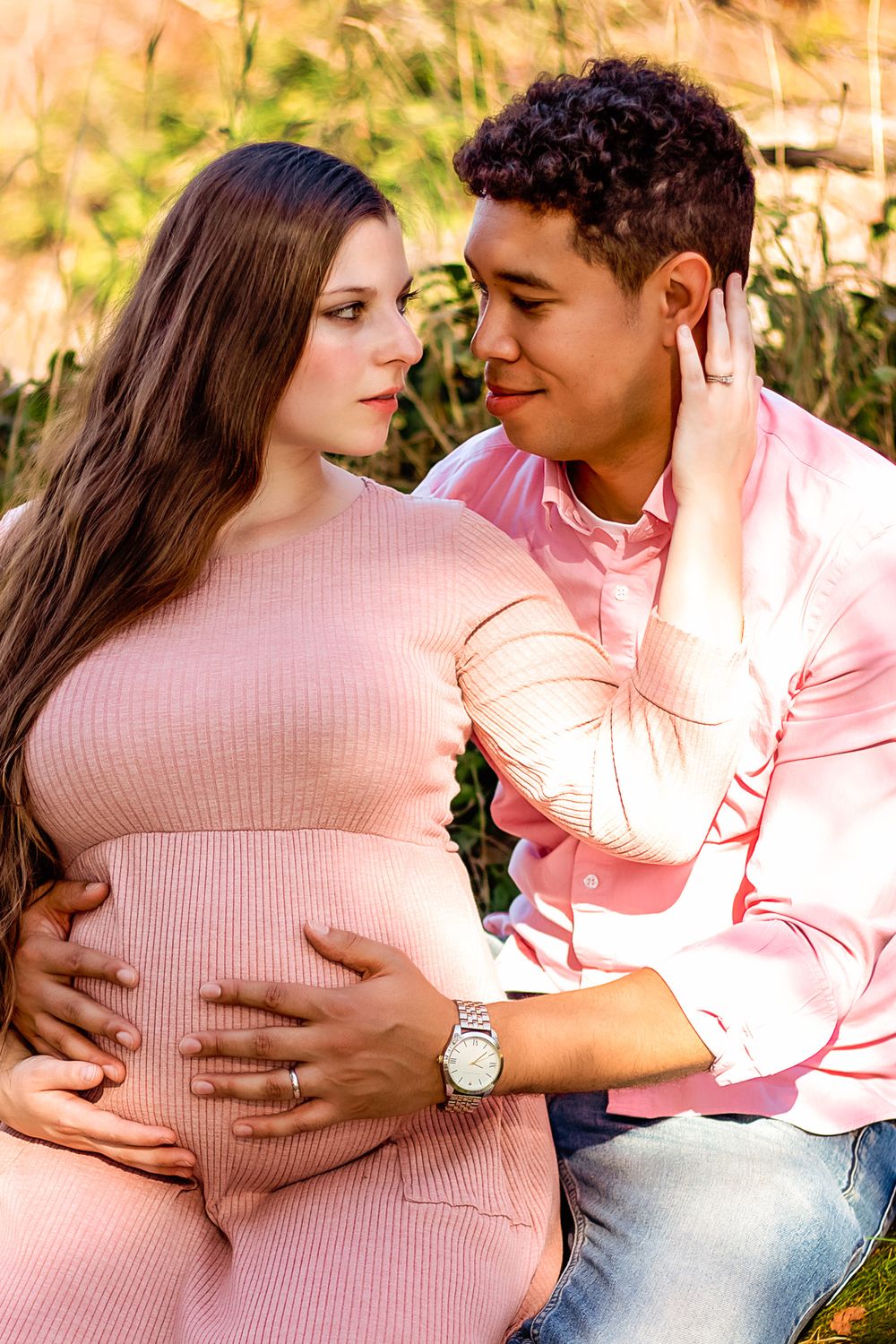 An expectant father smiling as he feels the movements of his unborn child