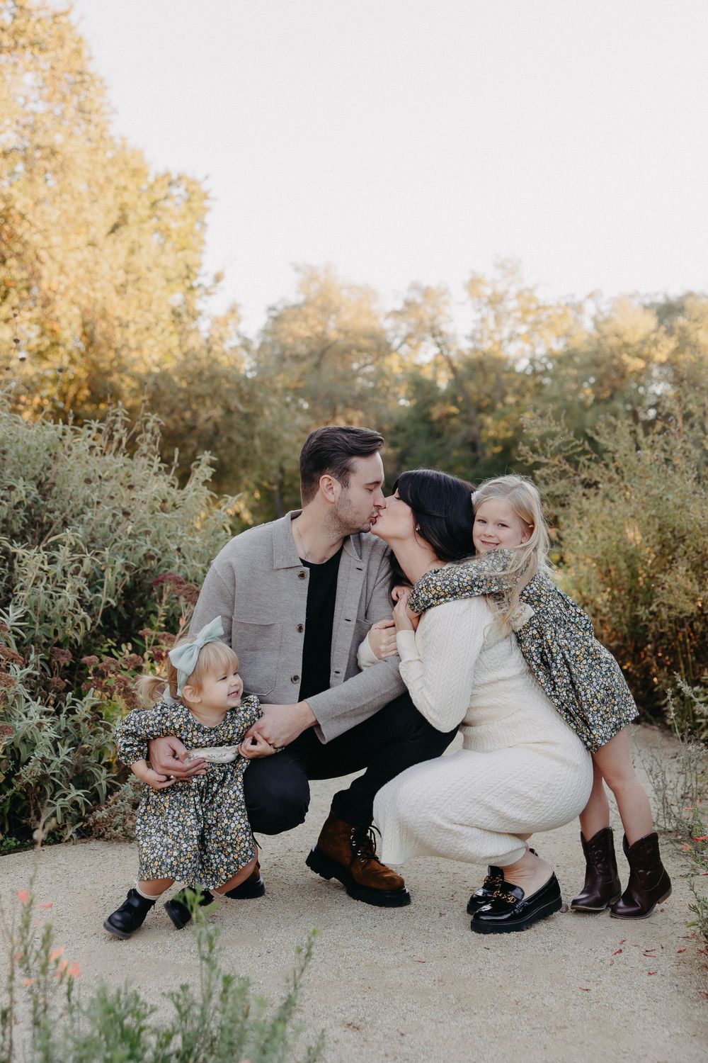 An intimate family moment captured in a garden setting with warm golden light.