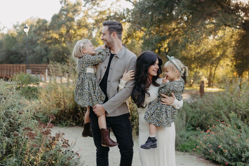 A joyful family moment captured on a nature path with golden sunlight filtering through trees.