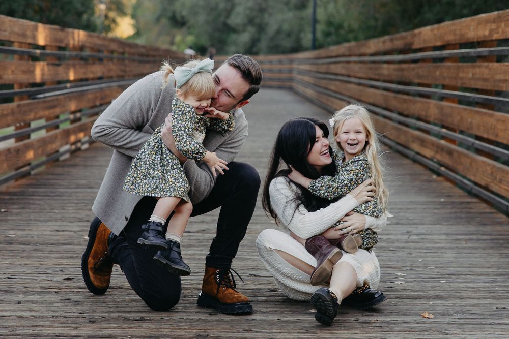 Happy family playing together on a rustic wooden bridge in a natural setting.