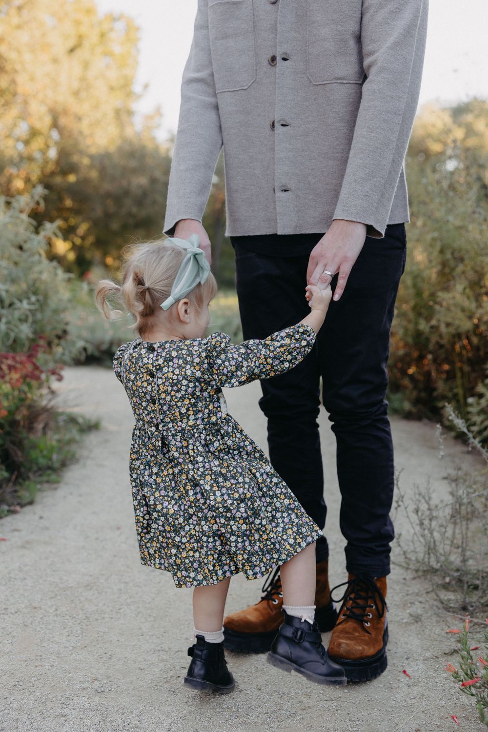 A sweet moment between parent and child holding hands on a garden path.