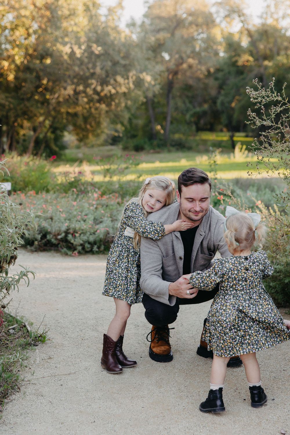 Playful family moment captured outdoors on a garden path with autumn foliage.