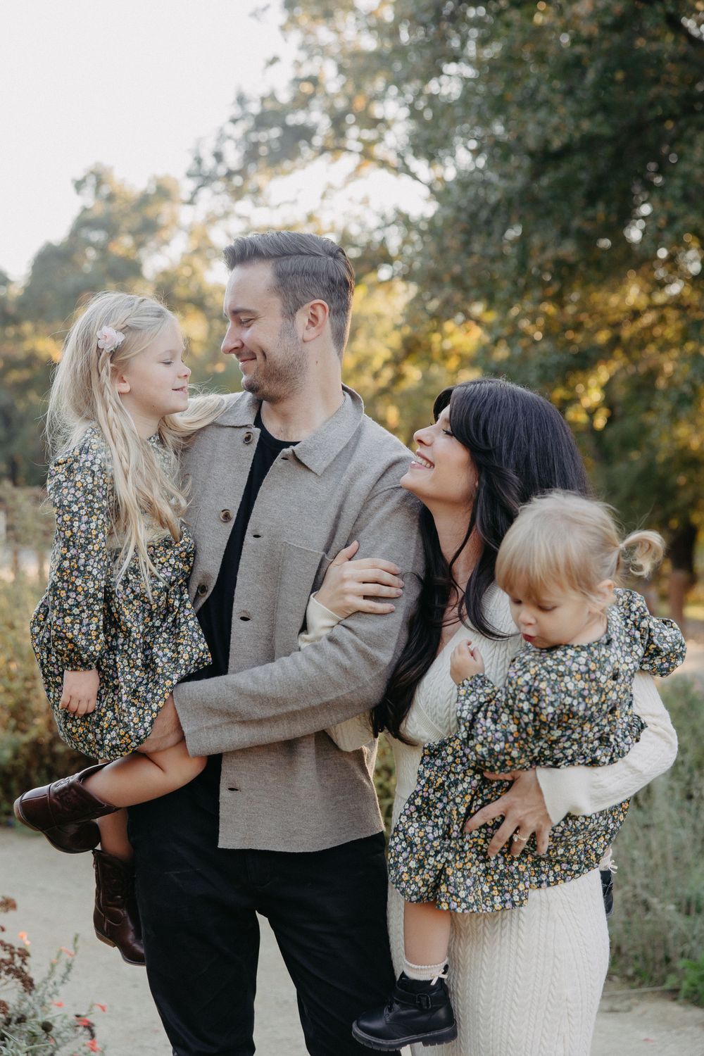 A candid family portrait showing natural laughter and joy in an outdoor garden setting.
