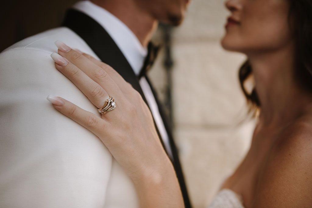 Close up of an engagement ring and wedding attire showing romantic intimacy.