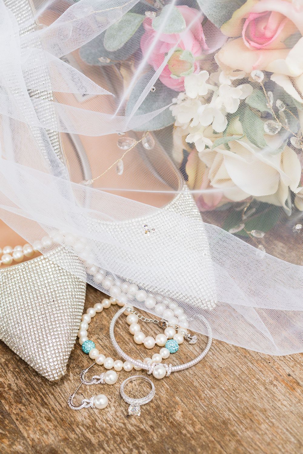 Bridal accessories including pearls, jewelry and sparkly shoes arranged with floral details and veil.