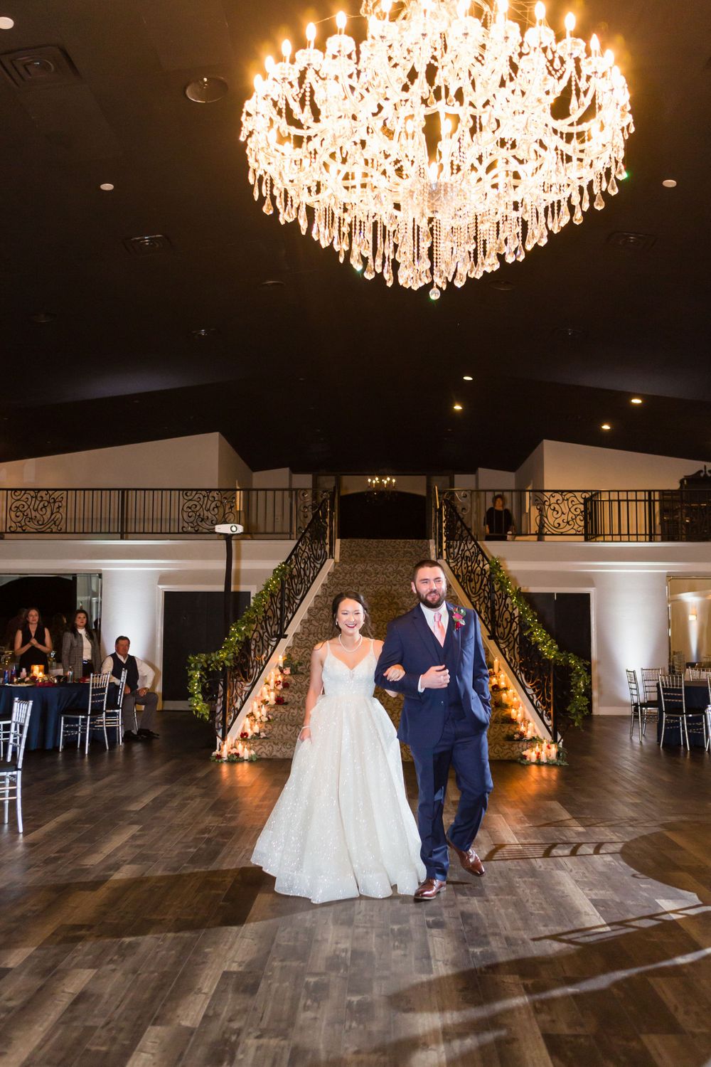 Elegant wedding venue with grand staircase, crystal chandelier, and warm lighting.