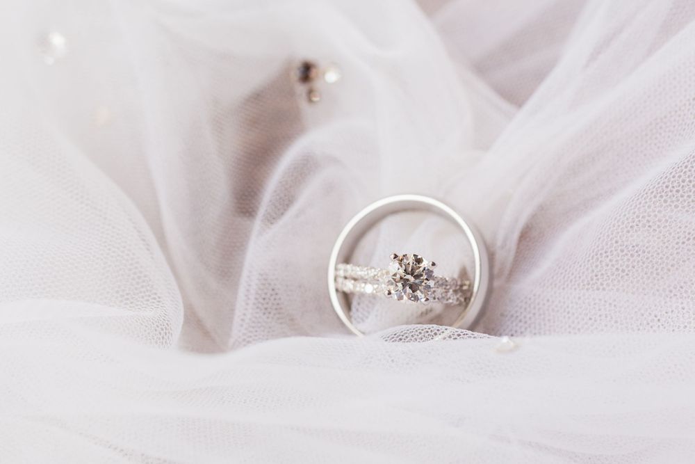 Diamond engagement ring photographed on white tulle fabric with soft focus effect.