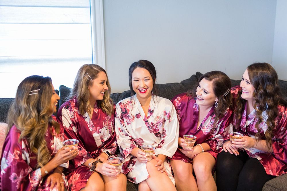 Group in matching floral robes share laughter on a grey couch.