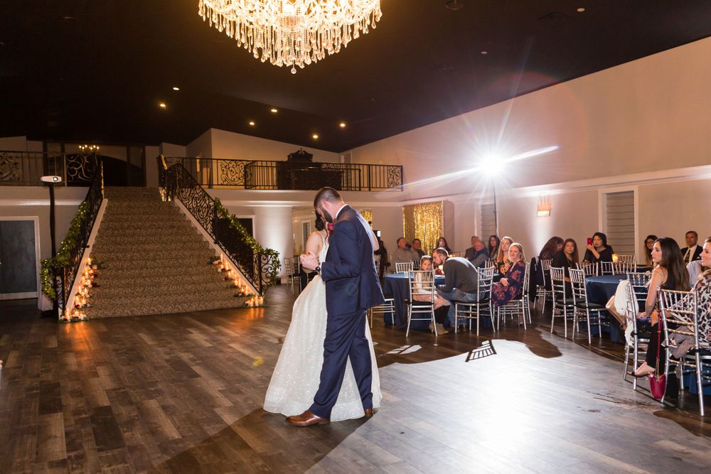Wedding reception venue with couple dancing while guests watch from decorated tables.