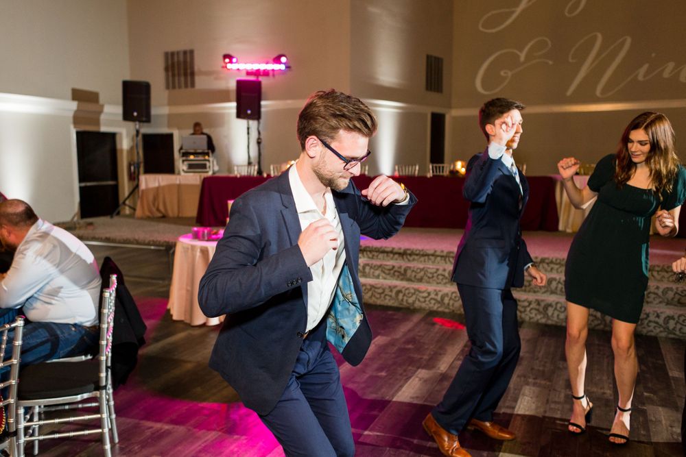 A guest shows off dance moves at a wedding reception with pink lighting effects.