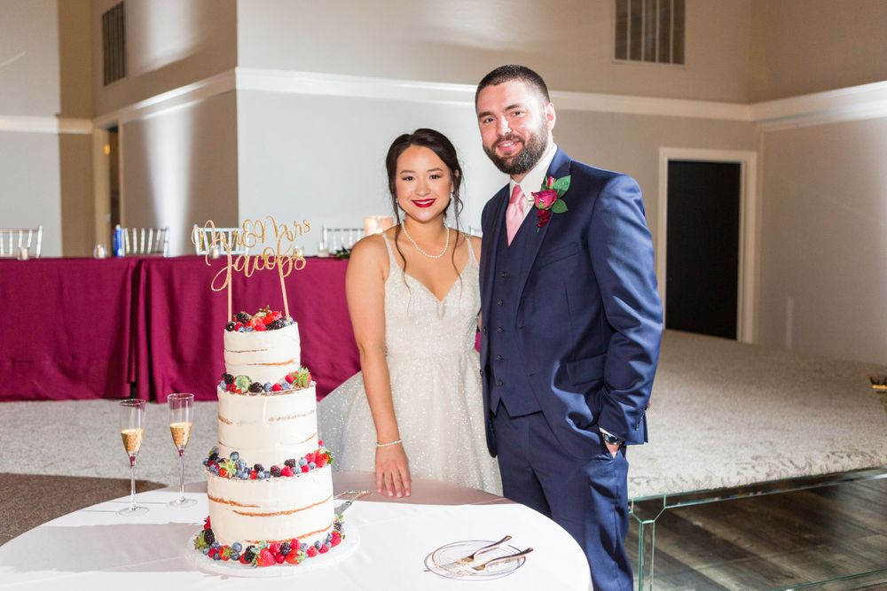 A stunning wedding cake display with burgundy accents and champagne flutes at an elegant reception.