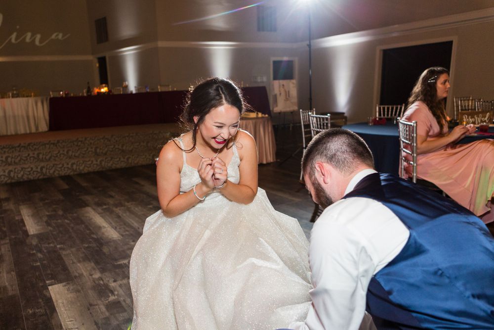A playful wedding moment on the dance floor during the garter toss tradition.