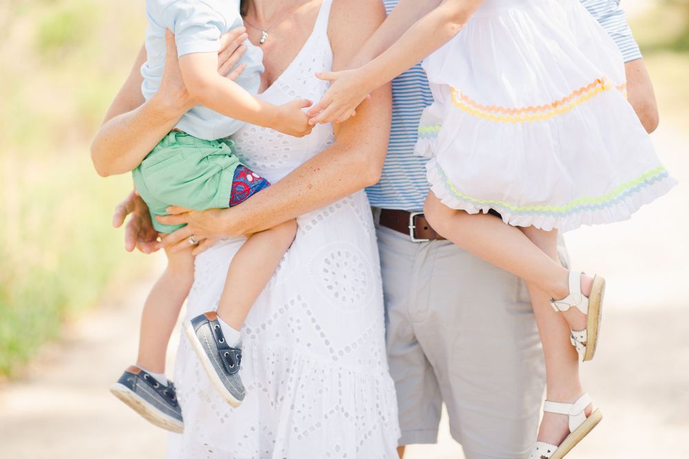 Parents holding children in white and casual clothing outdoors for a photo of sweet details and candid moments in Beaufort family photograph