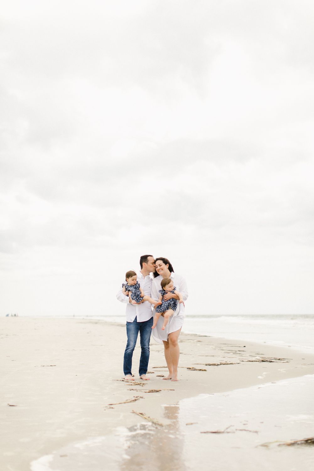 Family photography walking together along a serene beach on an overcast day in Sea Pines plantation located in Hilton Head, South Carolina.
