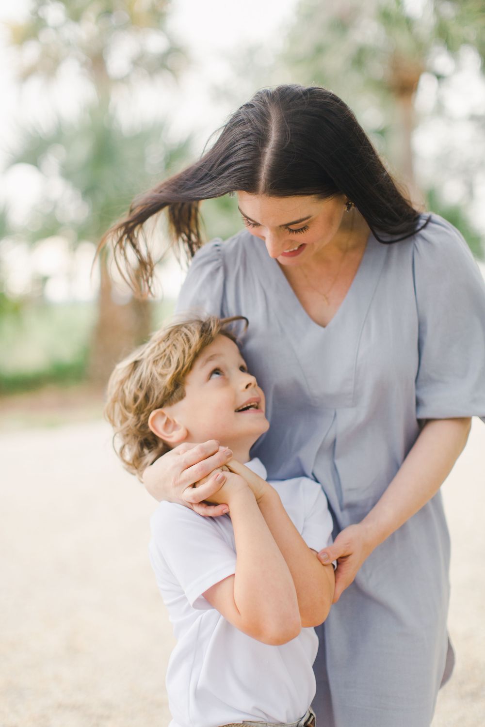 Beaufort photography of mother and young son share a tender candid moment outdoors in soft natural lighting. Near Habersham dock.