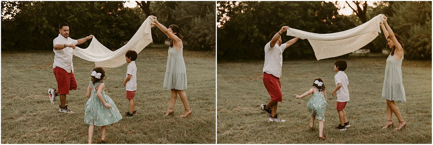 Joyful family moment playing with white fabric in a park during sunset.
