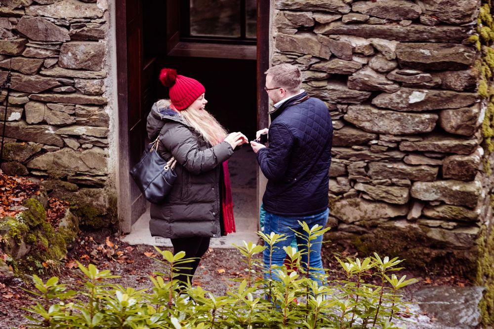People exploring the entrance of a rustic stone building with winter clothing.