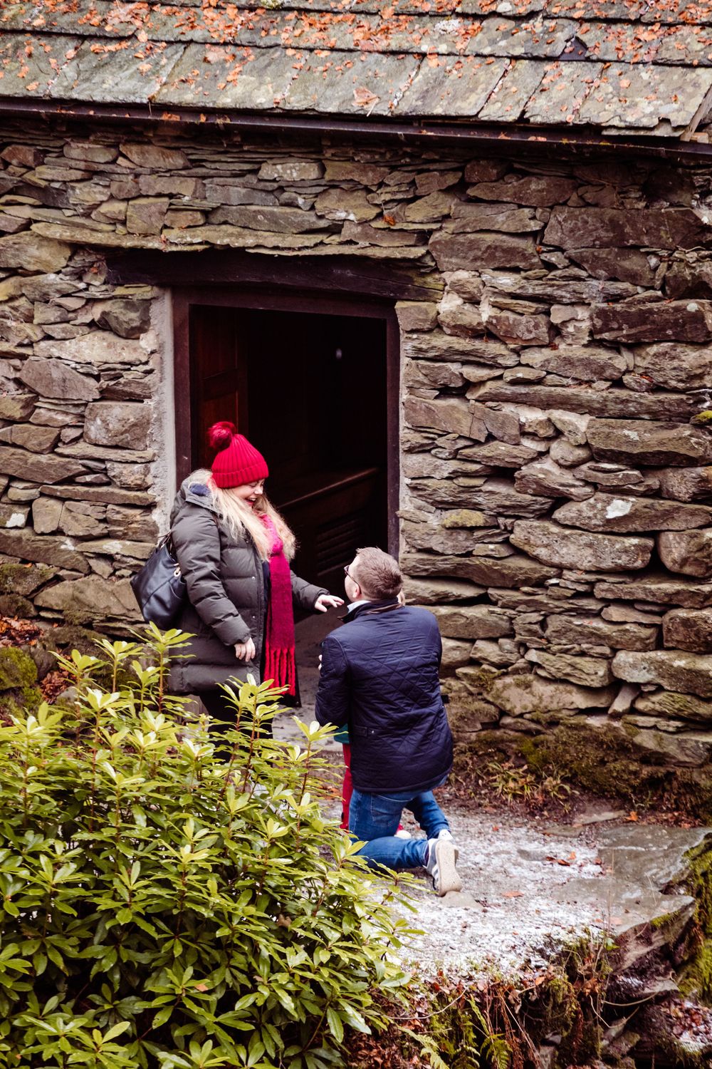 People enter a doorway of an old stone building during what appears to be a proposal moment.