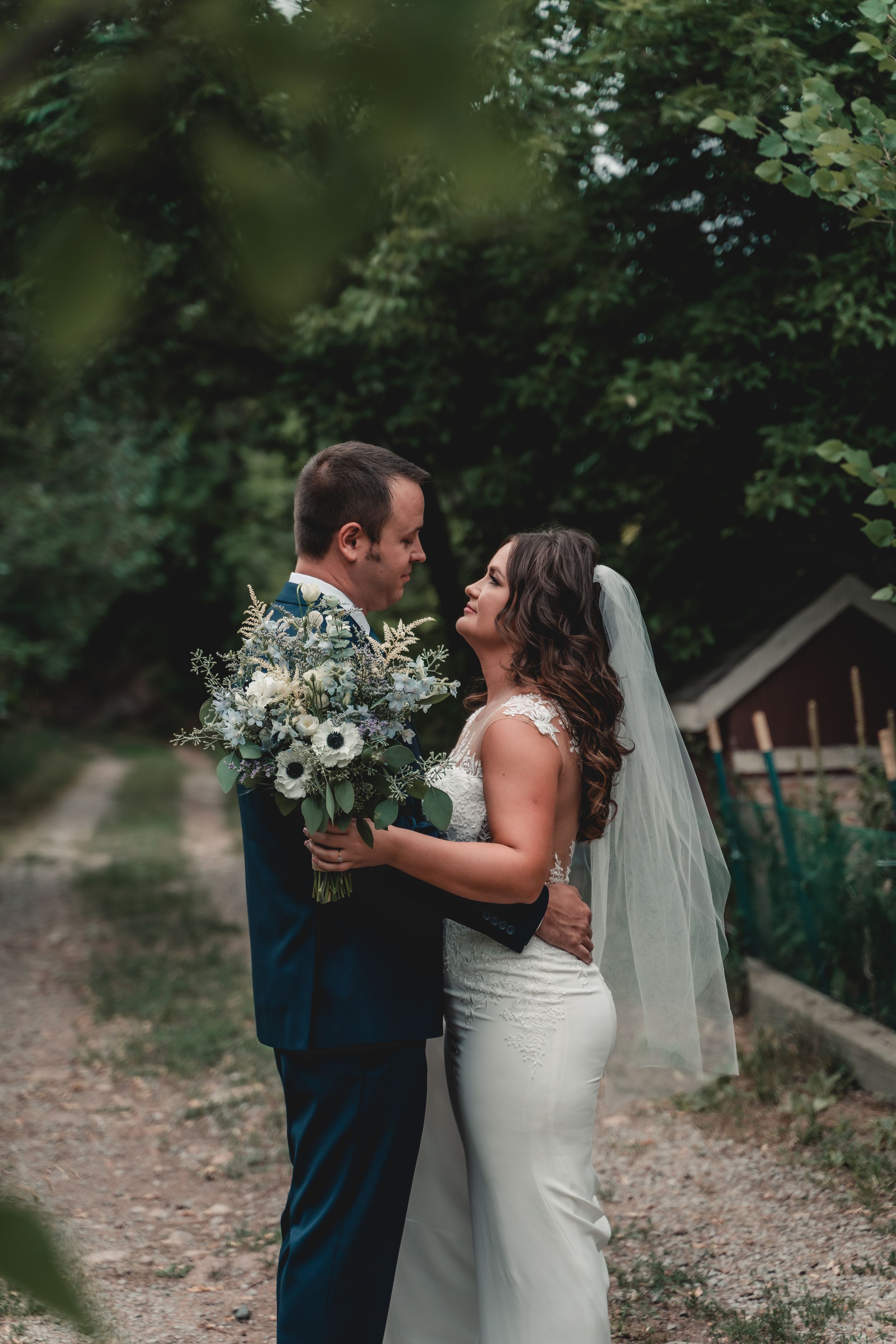 A romantic wedding portrait in a garden setting with a white bouquet.