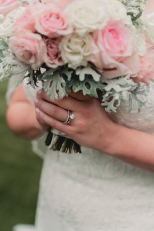 Close up of bridal bouquet with pink and white roses showing wedding ring detail.
