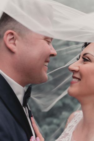 Romantic close-up of couple under flowing wedding veil.