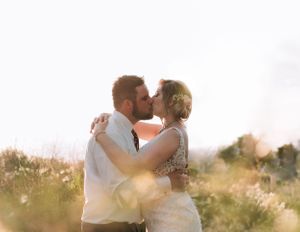 A romantic sunset embrace between newlyweds in a golden field.