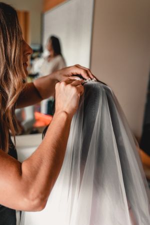 Close-up of hands adjusting a delicate white wedding veil.