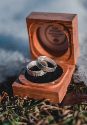 Two wedding rings nestled in a wooden box with detailed craftsmanship.