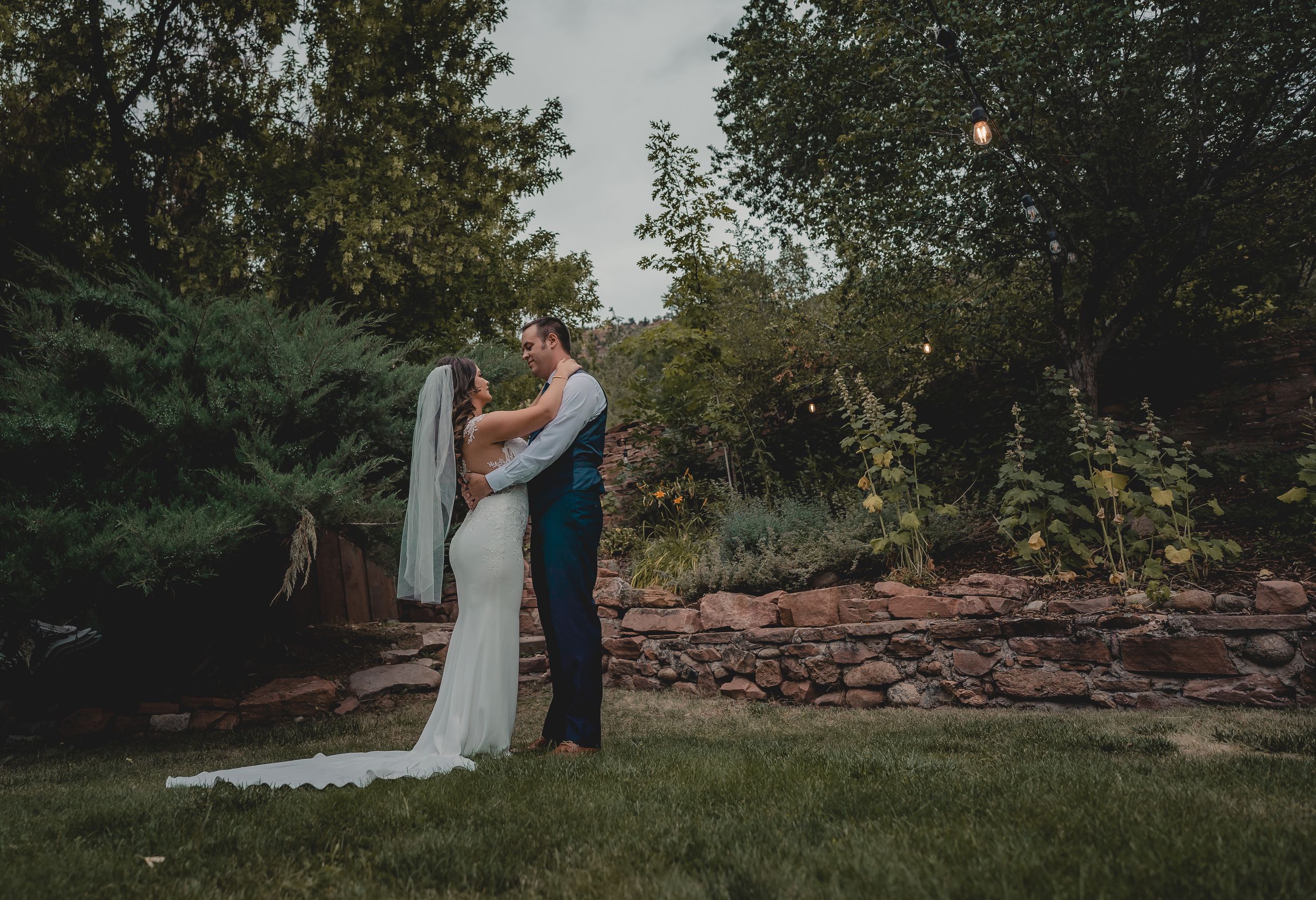 Newlyweds share a romantic moment in a garden at sunset.