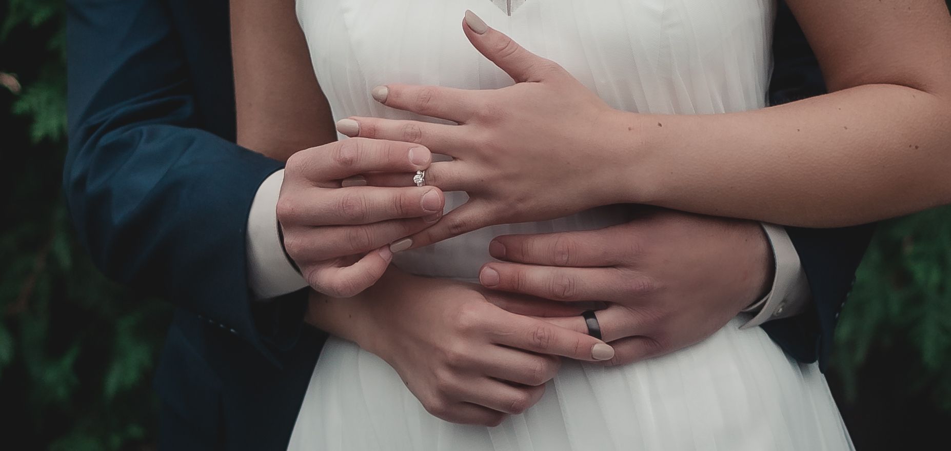 Intimate wedding photo showing hands with rings and formal attire.