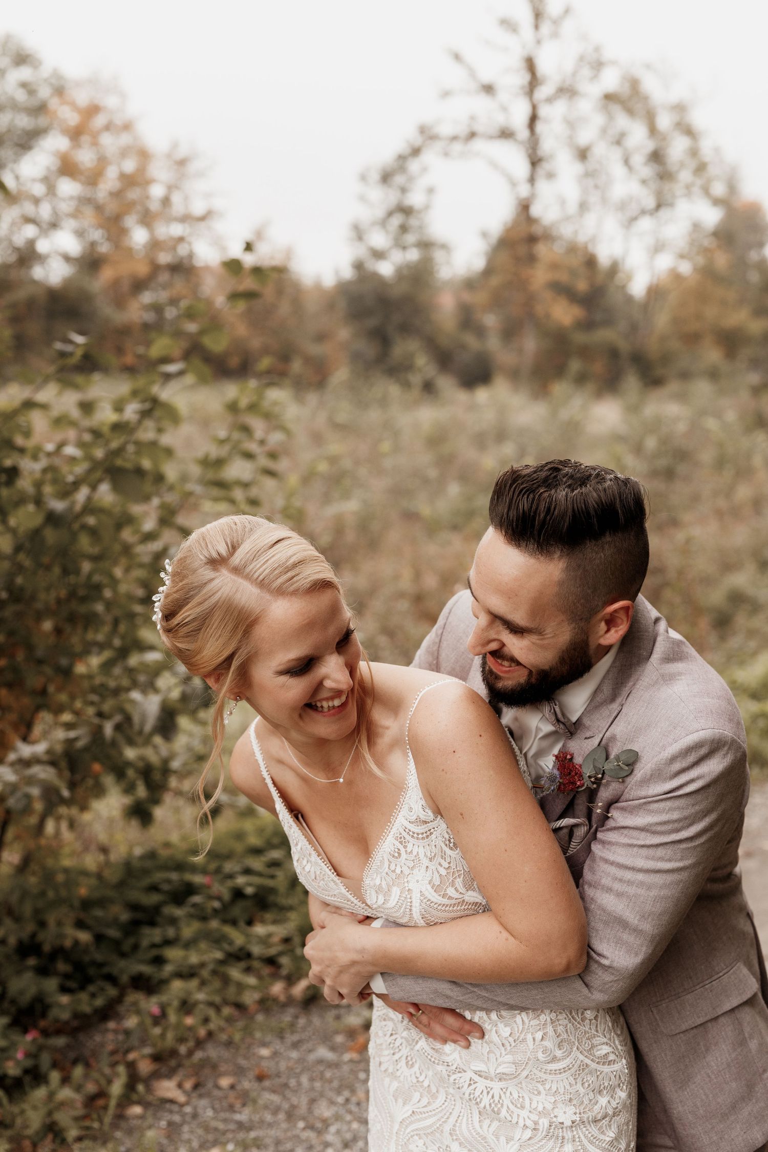 Glückliches Paar, das im Herbst in Hochzeitskleidung einen intimen Moment miteinander im Freien teilt.