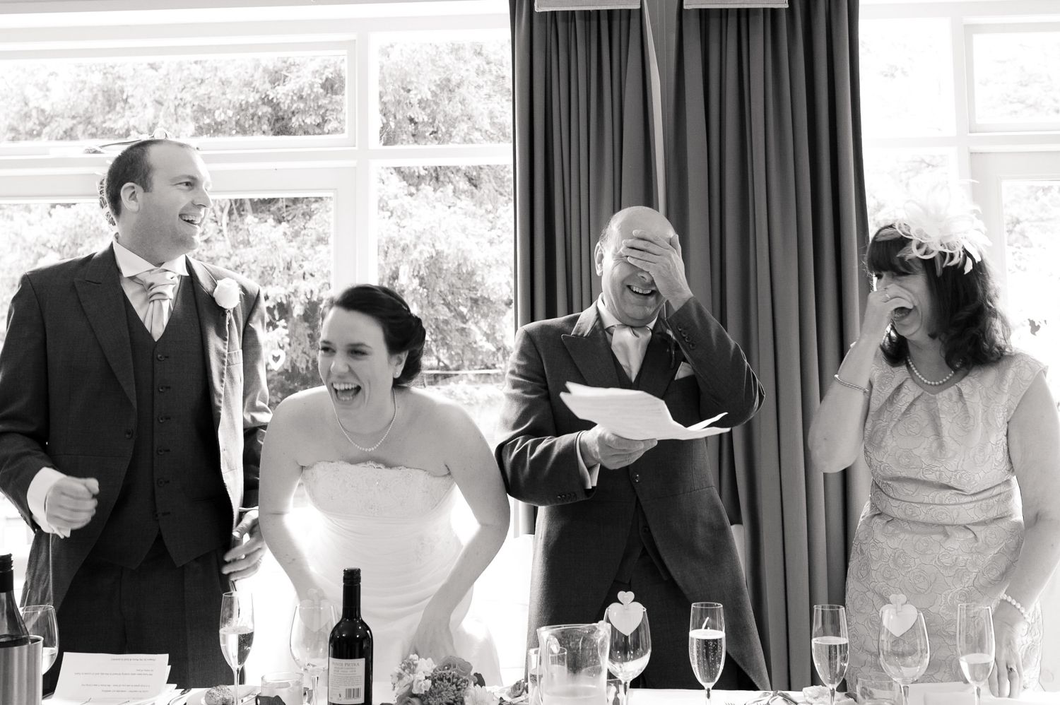 Black and white candid photo of wedding reception toasts and speeches.