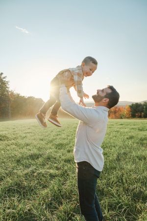 man throwing young boy in air outdoors
