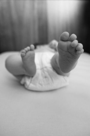 close up of baby feet in crib black and white
