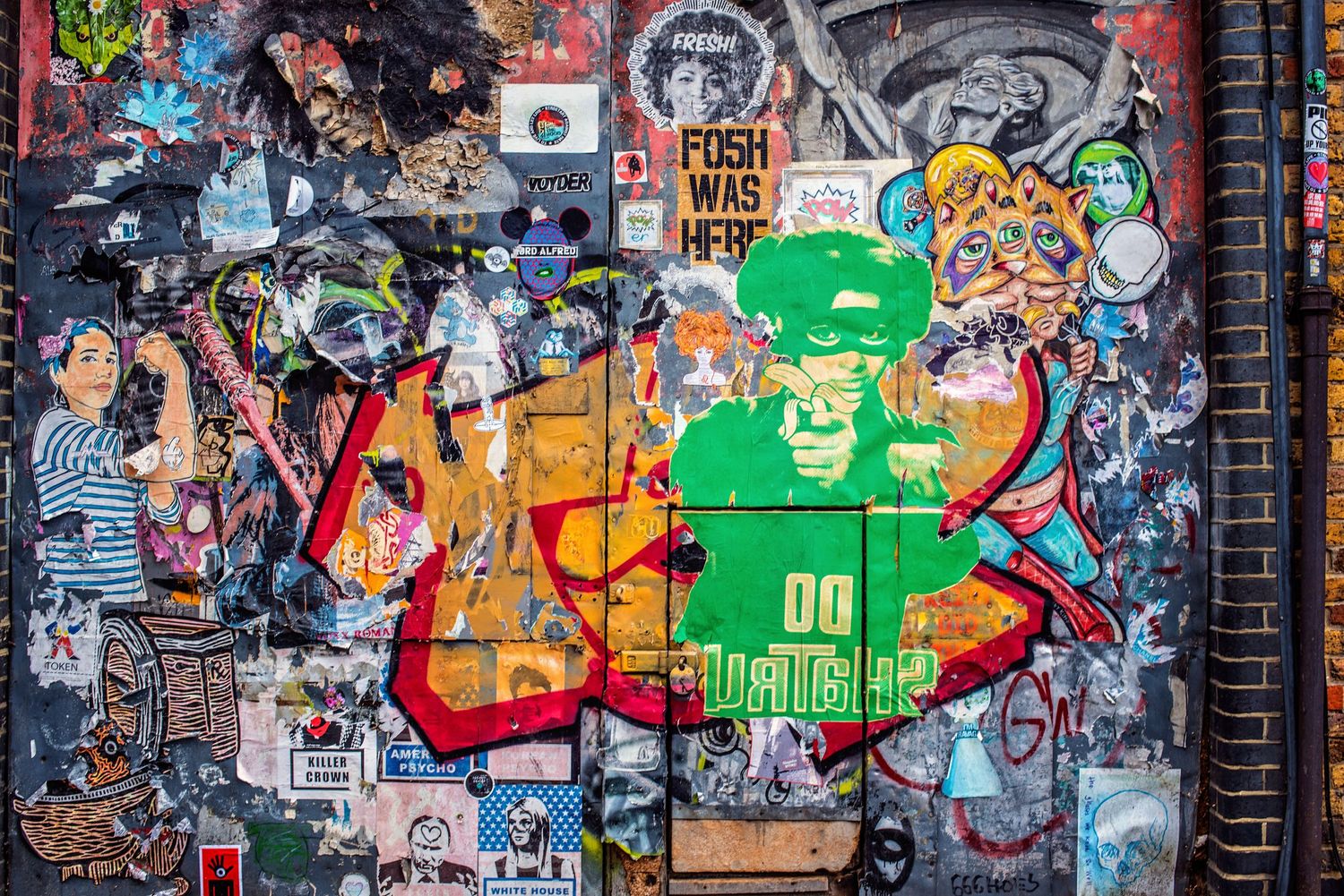 Vibrant graffiti street art featuring colorful characters and designs covers an urban wall with a mix of styles and tags.